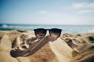 海滩沙滩上的黑色雷朋旅行太阳镜